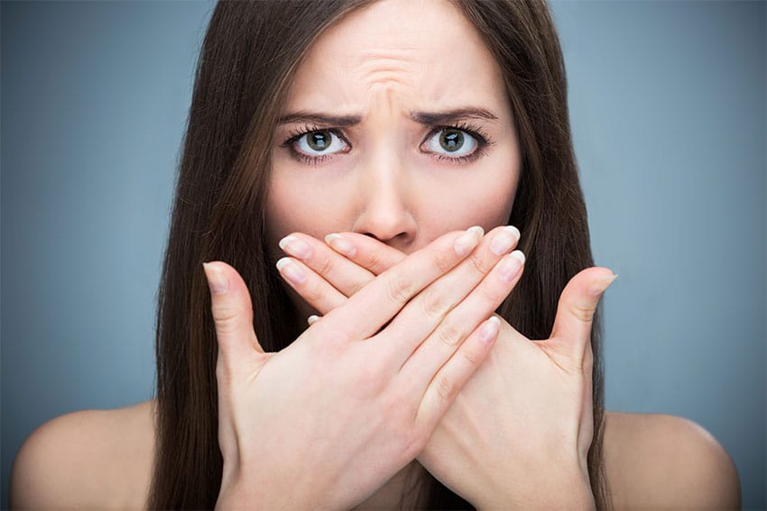 Young woman holding hands over her mouth