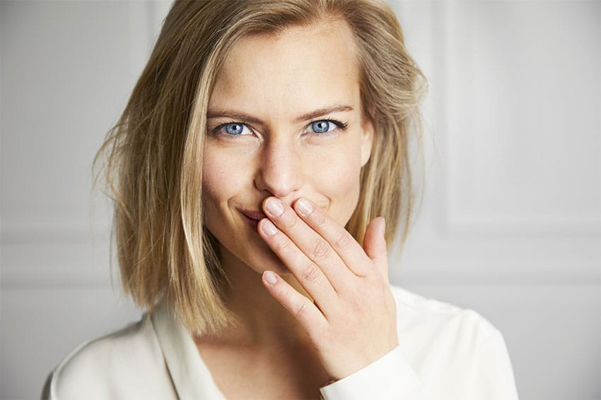 cute woman holds her hand up to her mouth